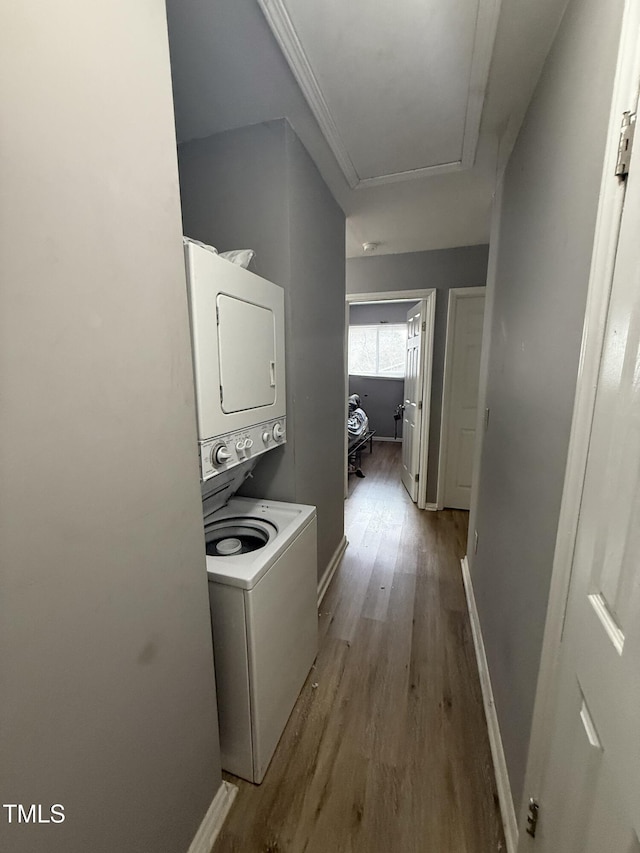 laundry area featuring stacked washer and dryer and light wood-type flooring