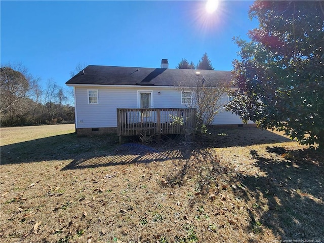 rear view of house featuring a wooden deck and a lawn