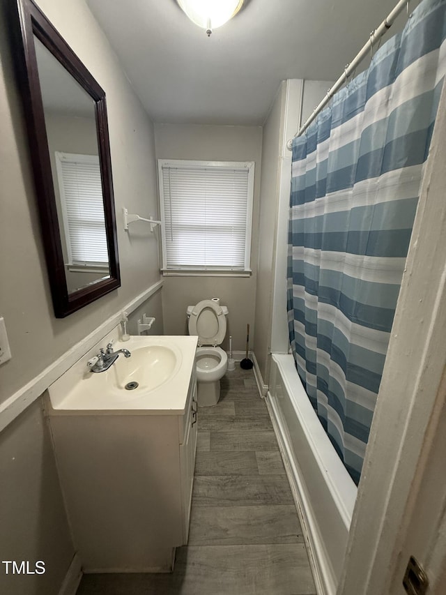 full bathroom with wood-type flooring, shower / tub combo with curtain, vanity, and toilet