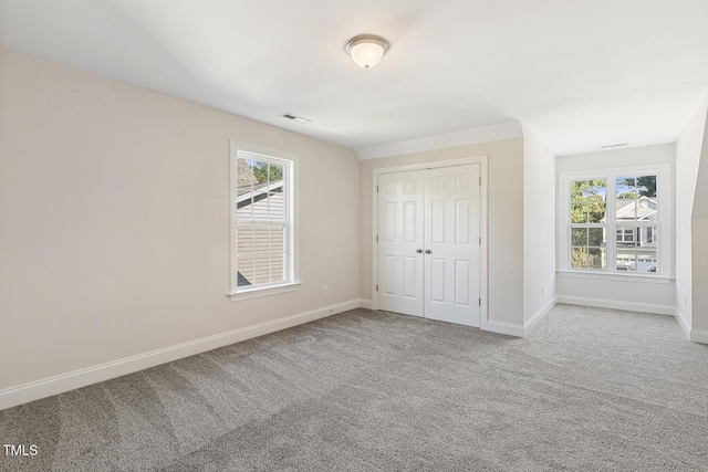 unfurnished bedroom with multiple windows, a closet, and carpet