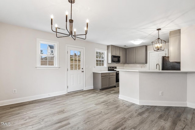 kitchen with electric stove, gray cabinets, refrigerator, hanging light fixtures, and a notable chandelier