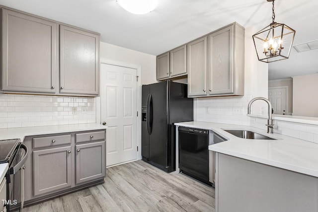 kitchen featuring gray cabinets, pendant lighting, sink, light hardwood / wood-style floors, and black appliances