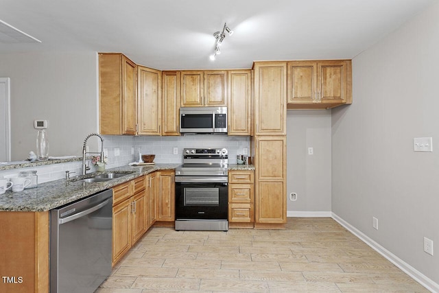 kitchen with sink, light hardwood / wood-style flooring, stainless steel appliances, light stone counters, and tasteful backsplash