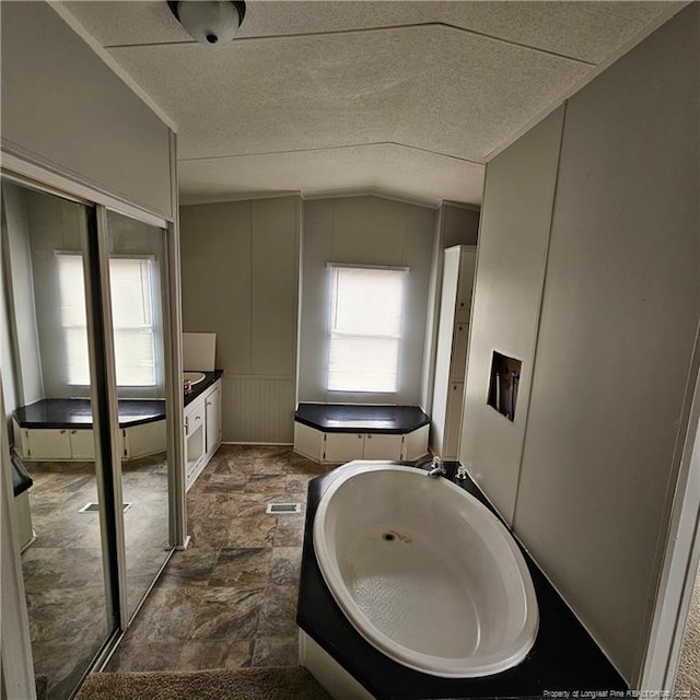 bathroom featuring a bathing tub and lofted ceiling