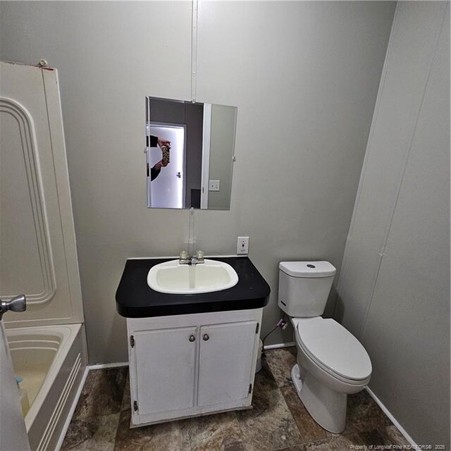 bathroom with vanity, a tub, and toilet