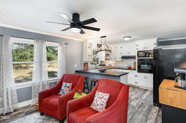 kitchen featuring pendant lighting, kitchen peninsula, white cabinets, and black appliances