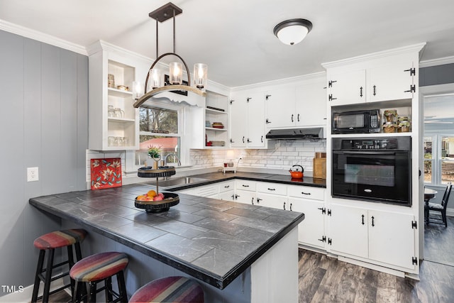 kitchen with black appliances, white cabinets, decorative light fixtures, tile countertops, and kitchen peninsula