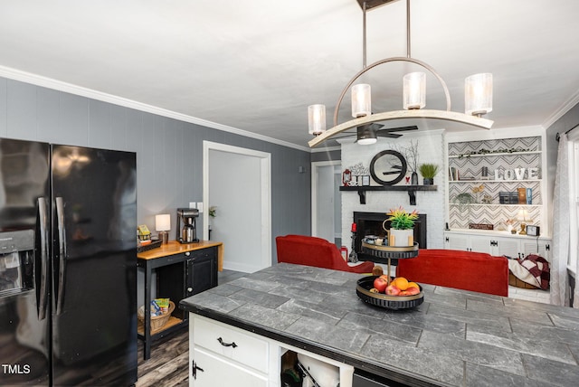 kitchen with white cabinetry, black fridge, a fireplace, and crown molding