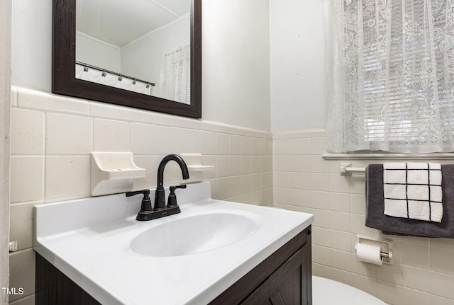 bathroom with vanity, toilet, and tile walls