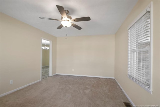 carpeted spare room featuring ceiling fan with notable chandelier