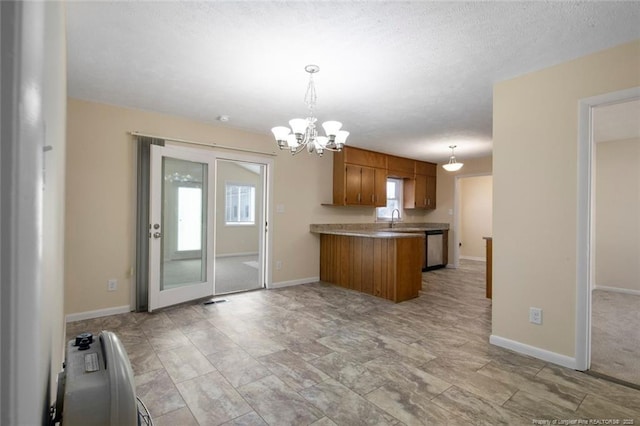 kitchen with decorative light fixtures, plenty of natural light, sink, and kitchen peninsula