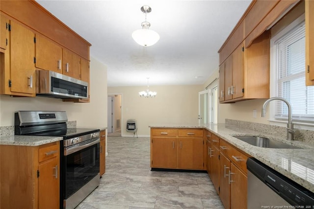 kitchen with sink, light stone counters, decorative light fixtures, appliances with stainless steel finishes, and kitchen peninsula