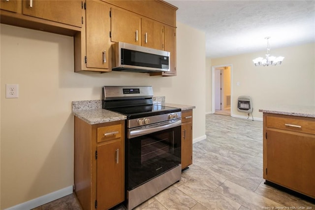 kitchen with heating unit, hanging light fixtures, a notable chandelier, stainless steel appliances, and light stone countertops