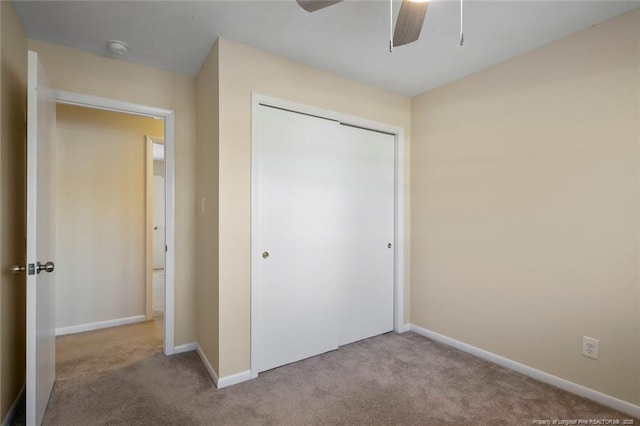 unfurnished bedroom featuring ceiling fan, a closet, and light carpet