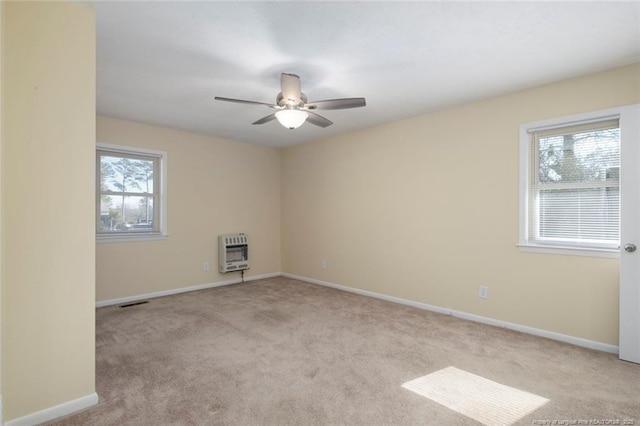 unfurnished room with heating unit, light colored carpet, and a healthy amount of sunlight