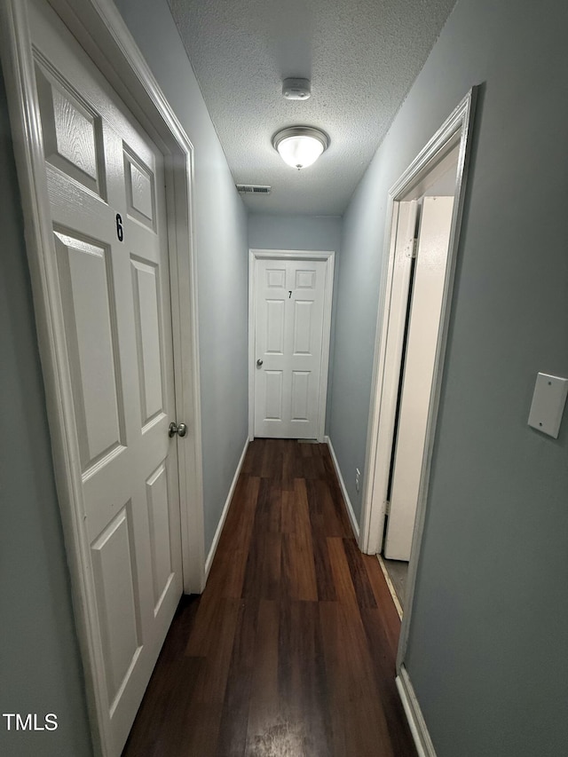 hallway featuring dark hardwood / wood-style floors and a textured ceiling