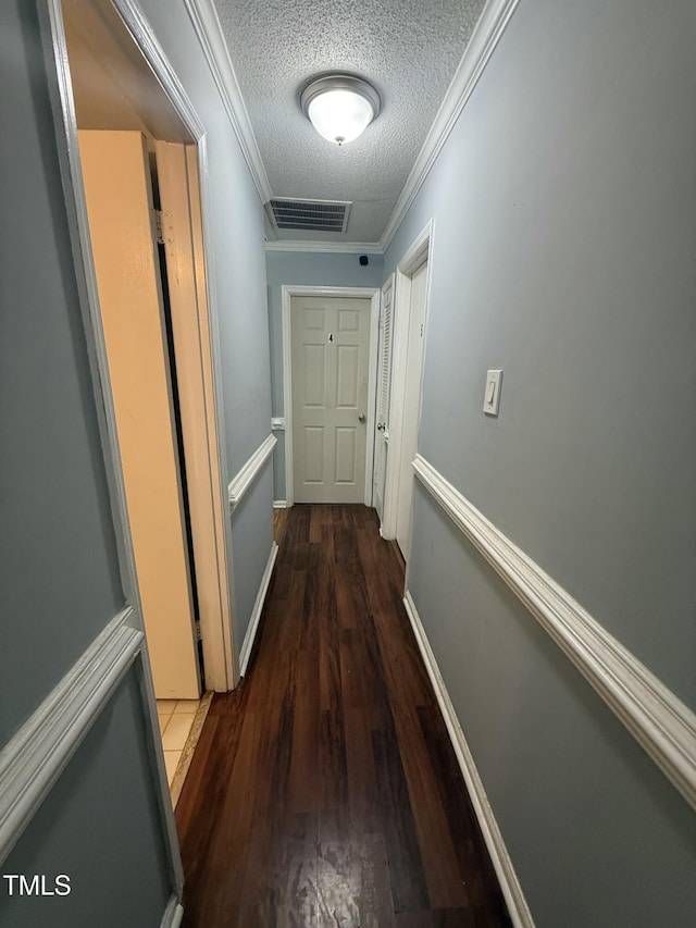 hall featuring ornamental molding, dark wood-type flooring, and a textured ceiling