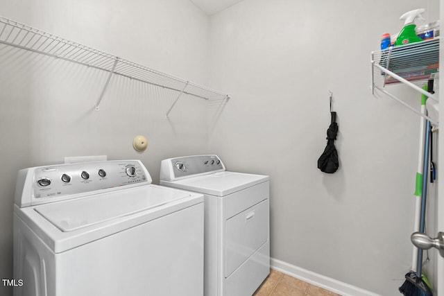 washroom featuring washer and dryer, laundry area, light tile patterned floors, and baseboards