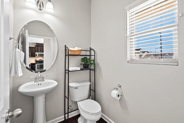 bathroom with toilet, baseboards, and a sink