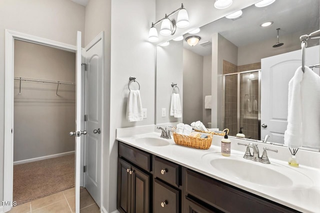 bathroom featuring tile patterned flooring, double vanity, a stall shower, and a sink