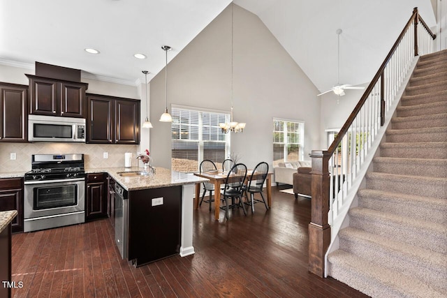 kitchen with a sink, light stone countertops, appliances with stainless steel finishes, and dark wood-style floors