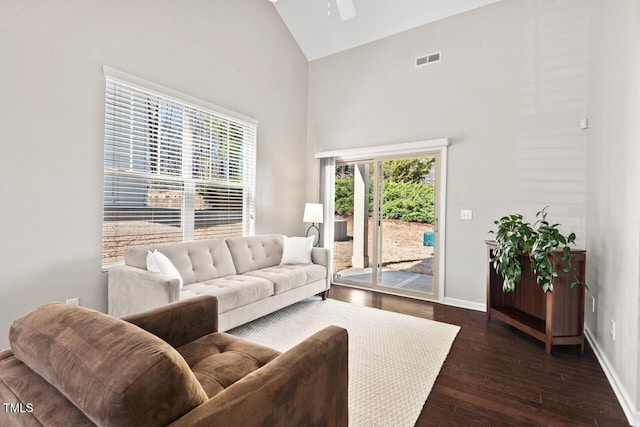 living area featuring dark wood-style floors, visible vents, high vaulted ceiling, and baseboards