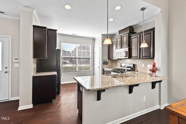 kitchen with a breakfast bar, backsplash, stainless steel appliances, crown molding, and dark wood-style flooring