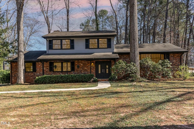 view of front facade featuring brick siding and a front yard