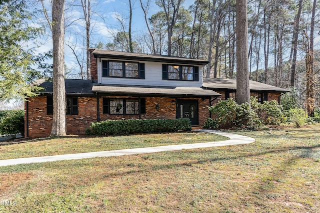 view of front of house featuring brick siding, a chimney, and a front yard