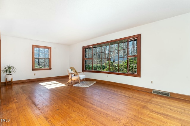 unfurnished room with visible vents, baseboards, and hardwood / wood-style flooring