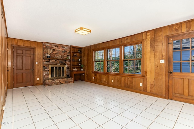 unfurnished living room with light tile patterned floors, wooden walls, and a fireplace