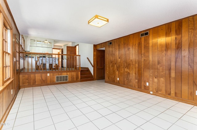 empty room with stairway, wooden walls, and visible vents