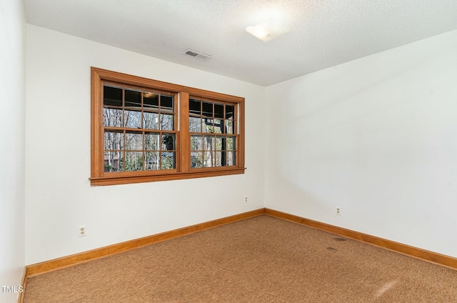 carpeted empty room featuring visible vents, baseboards, and a textured ceiling