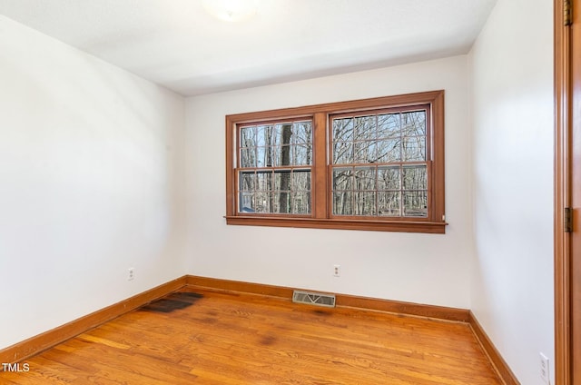 spare room with visible vents, baseboards, plenty of natural light, and wood finished floors