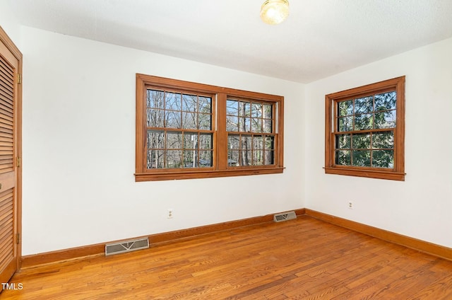 spare room with visible vents, baseboards, and wood-type flooring