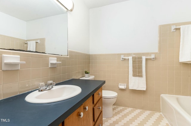 bathroom featuring tile patterned floors, toilet, a tub, tile walls, and vanity