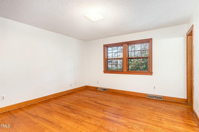 empty room with visible vents, light wood-style flooring, and a textured ceiling