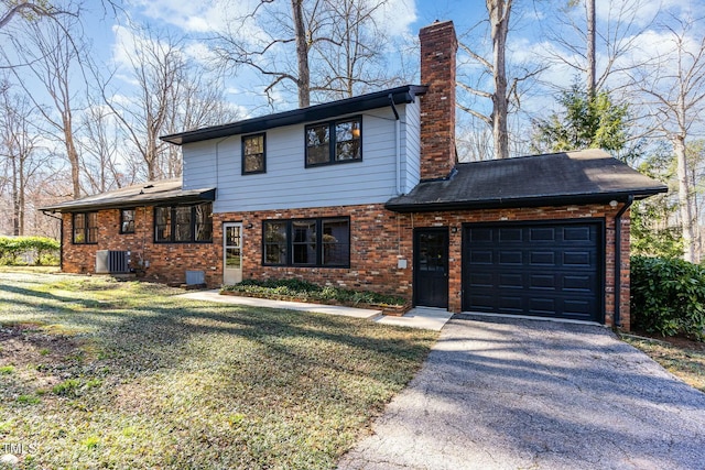 tri-level home with a front yard, brick siding, a chimney, and an attached garage