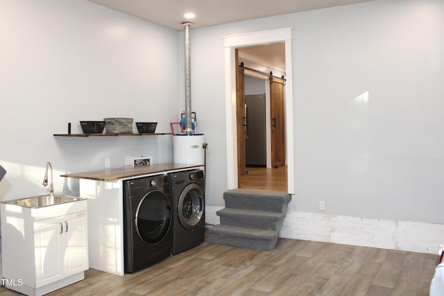 5920 Whittier Dr, Raleigh, NC 27609 - clothes washing area featuring a barn door, light wood-style flooring, washer and clothes dryer, and cabinet space