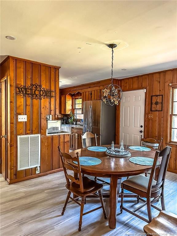 dining space with sink, wooden walls, and light hardwood / wood-style floors