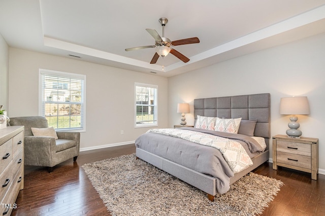 bedroom featuring dark hardwood / wood-style floors, ceiling fan, and a tray ceiling