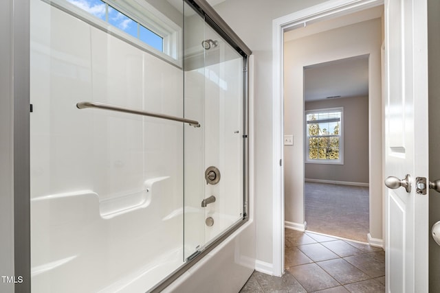 bathroom with bath / shower combo with glass door and tile patterned flooring