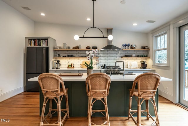 kitchen featuring light hardwood / wood-style floors, a kitchen bar, and wall chimney exhaust hood