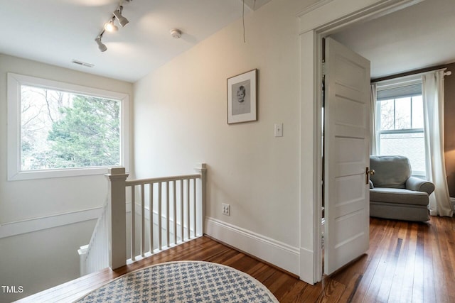 corridor featuring dark hardwood / wood-style flooring and rail lighting