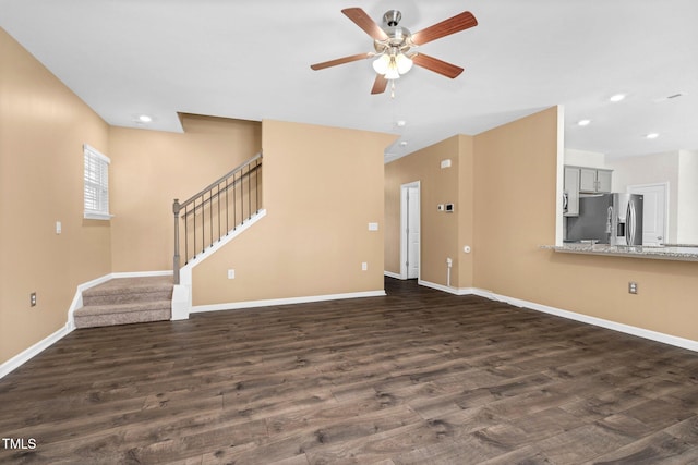 unfurnished living room with dark hardwood / wood-style flooring and ceiling fan