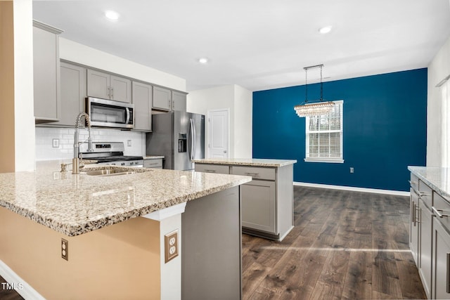 kitchen featuring pendant lighting, appliances with stainless steel finishes, a kitchen island, and gray cabinetry