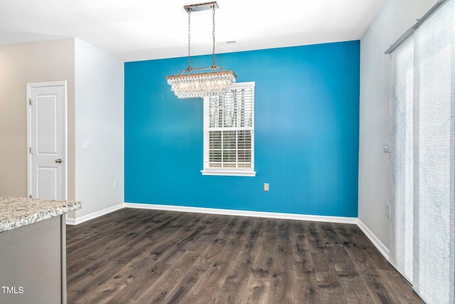 unfurnished dining area with a healthy amount of sunlight, dark hardwood / wood-style flooring, and a notable chandelier