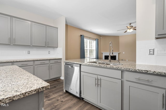 kitchen featuring gray cabinetry, sink, light stone counters, and stainless steel dishwasher