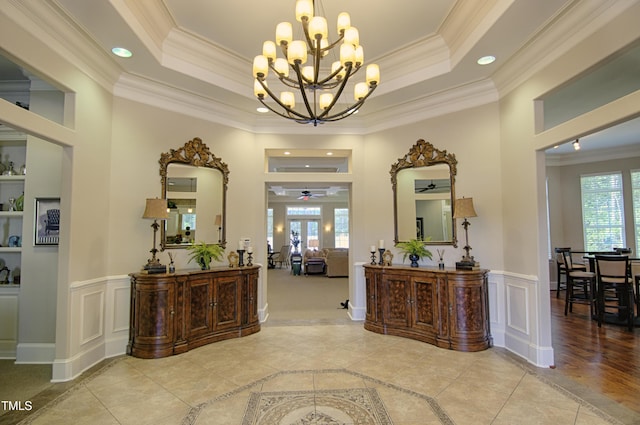 hallway with crown molding, a raised ceiling, and light tile patterned floors