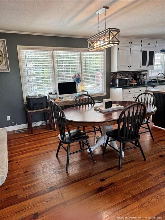 dining space featuring crown molding, a healthy amount of sunlight, dark hardwood / wood-style floors, and sink